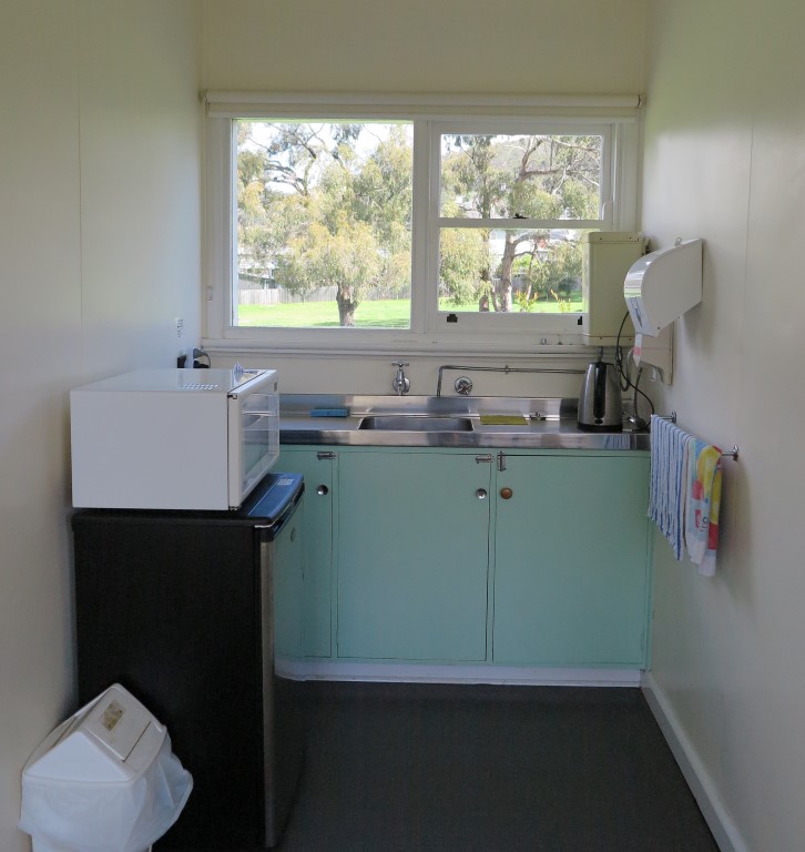 Kitchenette with microwave, small fridge and kettle and sink.